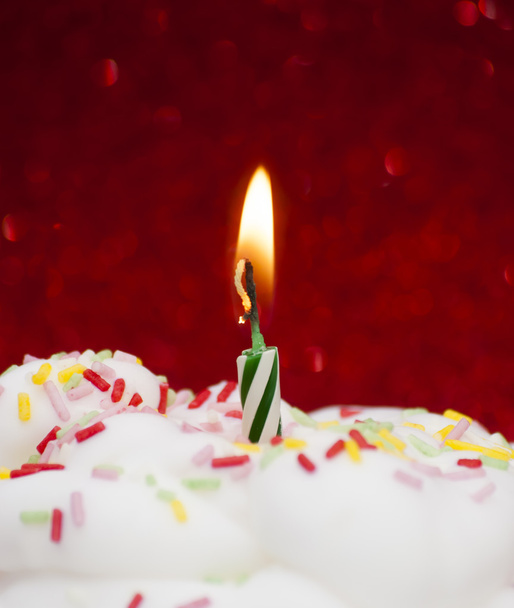 Cupcake with a lit candle over bright red background - Photo, image