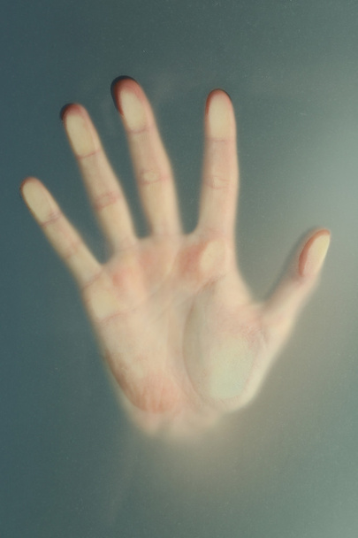 Female hand behind  wet glass, close-up - Foto, afbeelding