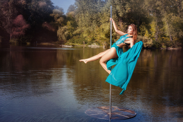 Girl in blue dress is spinning on a pole. - Photo, Image