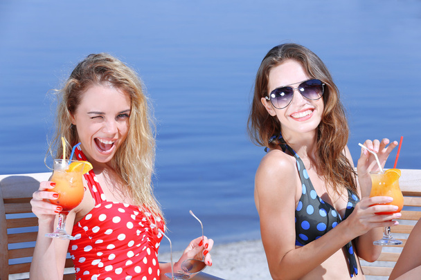 Two young girls enjoying cocktails on beach - Zdjęcie, obraz