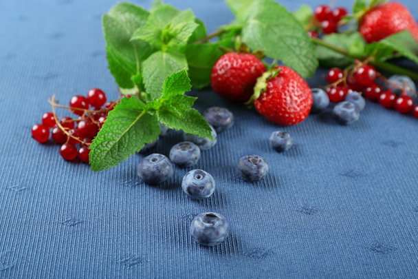 Group of fresh summer berries with mint on blue tablecloth background - Foto, Bild