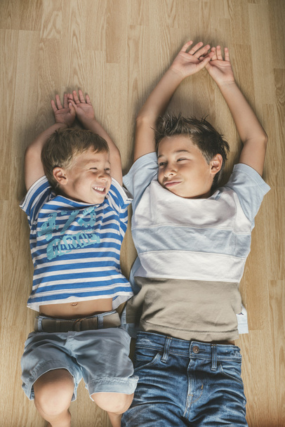 Cute joyful brothers kids lying on a floor at home. - Fotografie, Obrázek