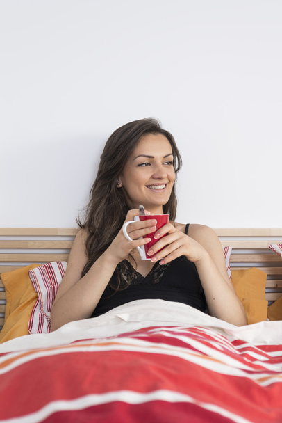 Young woman sleepy girl relaxing on bed at morning with cup of t - Фото, зображення