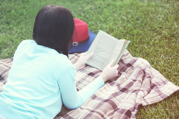 Mujer joven con libro acostado en la hierba verde al aire libre
 - Foto, Imagen