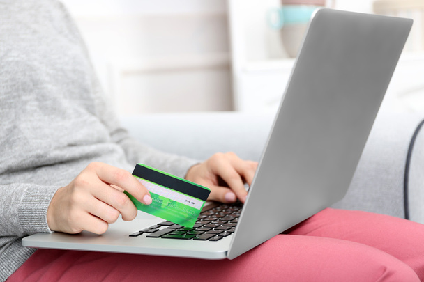 Koncept pro internetové nakupování: žena s notebookem a kreditní karty, sedí na gauči doma - Fotografie, Obrázek
