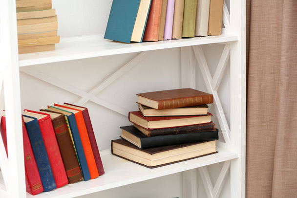 Books on shelves on white wall background - Foto, imagen