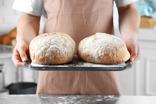 Baker checking freshly baked bread in kitchen of bakery - Zdjęcie, obraz
