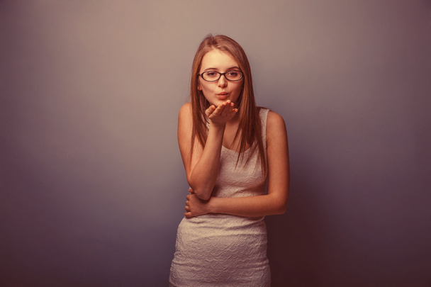 Europese uitziende meisje in glazen twintig jaar, stuurt een kus op een - Foto, afbeelding