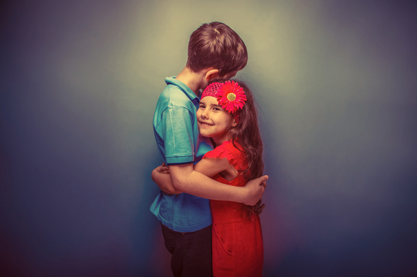 дівчина-підліток обіймає хлопчика-підлітка на сірому фоні ретро
 - Фото, зображення