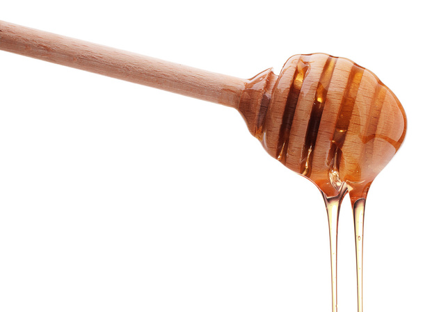 Honey dripping from wooden honey dipper - Fotoğraf, Görsel