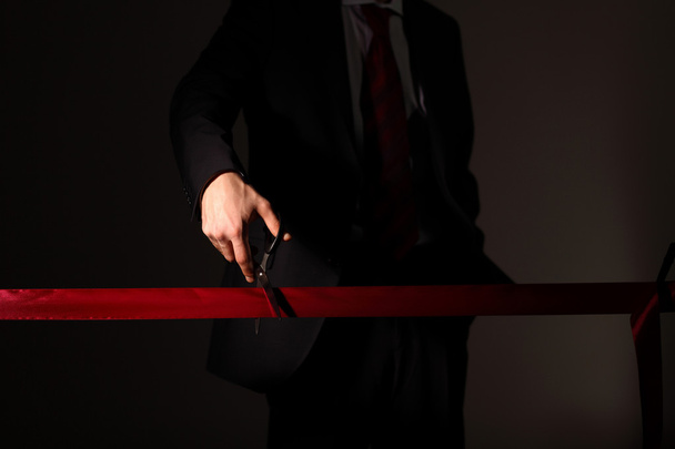 Empresario con tijeras cortando una cinta roja
 - Foto, Imagen