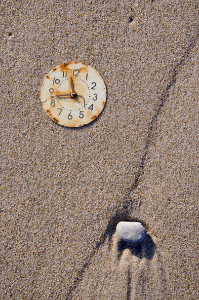Ржавый циферблат с часами на песке
 - Фото, изображение