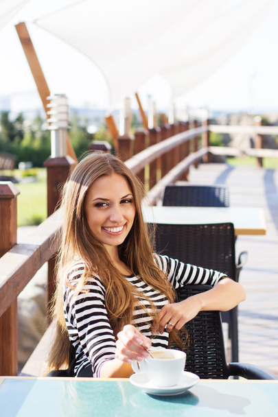 Smiling girl is drinking hot coffee outdoors - Photo, image