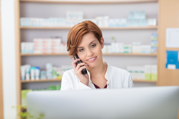 Pretty young pharmacist talking on a telephone - Фото, изображение