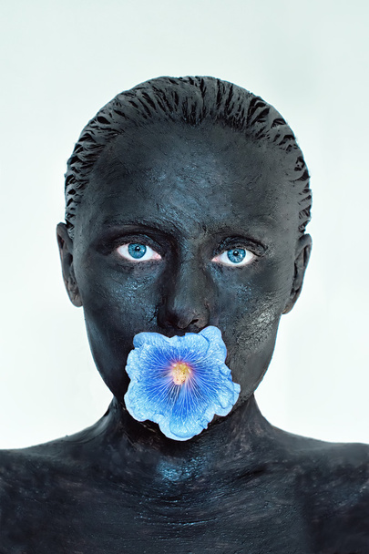 Bőrápolás. Nő agyagiszap maszk arcon, hallani és vállára kék virág a szájába elszigetelt fehér. Szépségápolás és wellness koncepció. - Fotó, kép