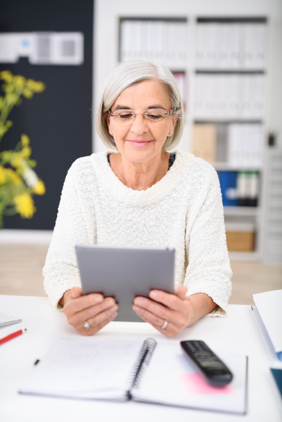 Senior businesswoman sitting reading a tablet - Foto, immagini