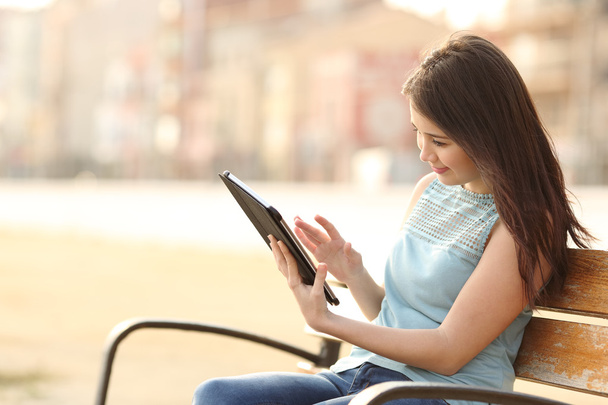 Girl reading an ebook or a tablet in a park - Fotoğraf, Görsel