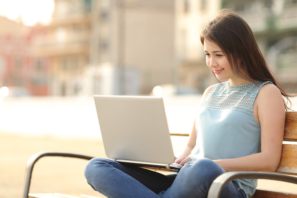 Student girl browsing a laptop sitting in a bench - Photo, image