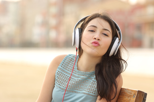 Menina adolescente com fones de ouvido beijando na câmera
 - Foto, Imagem