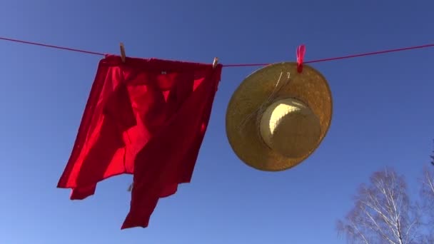 sombrero de mimbre y una camisa roja colgando de la cuerda y agitando en el viento
 - Metraje, vídeo