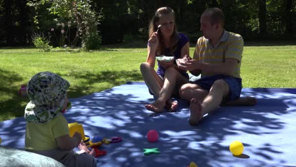 Gelukkige familie eten ijs op plaid en schattige baby blik bij hen. 4k - Video