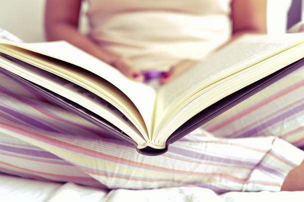 молодая женщина читает книгу в постели - Фото, изображение