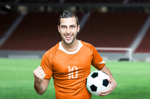 Fútbol fan celebra en camiseta naranja
 - Foto, Imagen