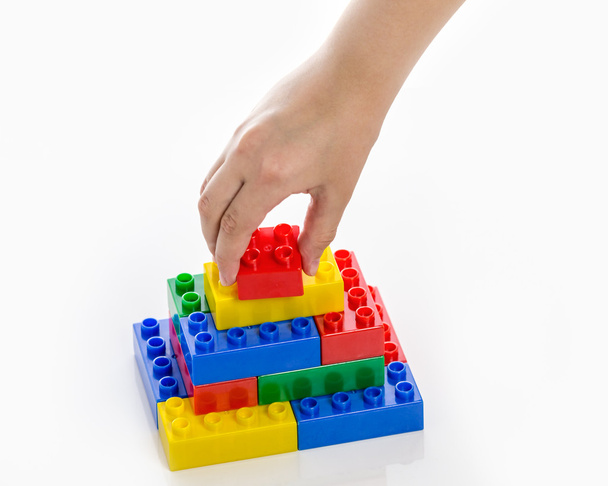 Hand completing colorful plastic brick structure - Фото, изображение