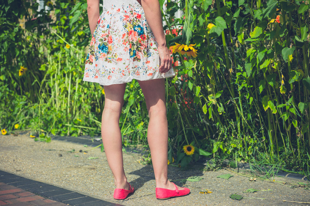 Kobieta w sukni stojącej przez słoneczniki - Zdjęcie, obraz