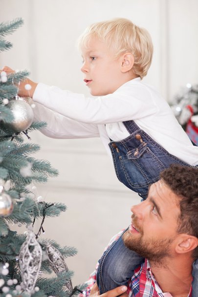 Cheerful family is preparing Christmas tree for celebration - Fotografie, Obrázek