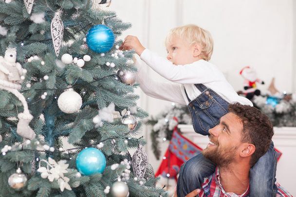 Pretty man and child are decorating New Year tree - Photo, Image
