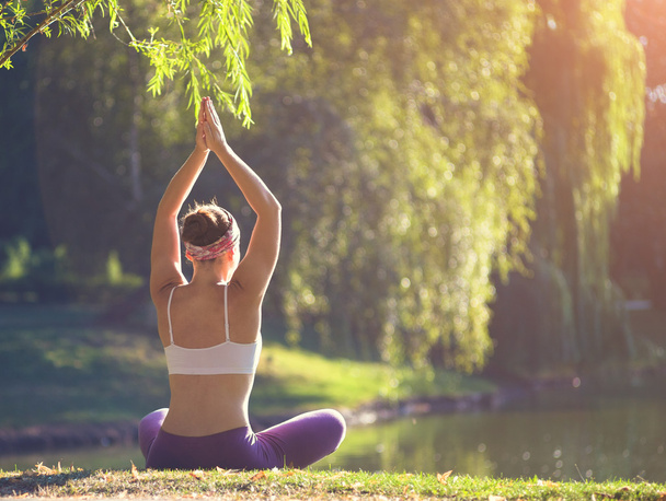 Young woman doing yoga in morning park - Photo, Image