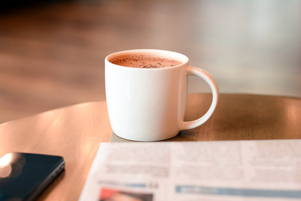 Tazza da caffè con giornale e telefono cellulare su tavolo di legno
 - Foto, immagini