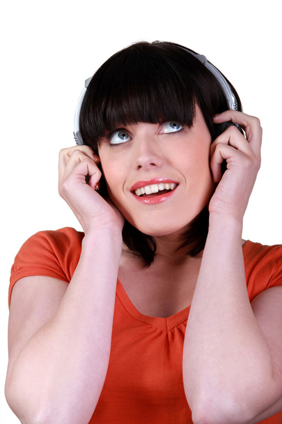 Brunette listening to music through headphones - Zdjęcie, obraz