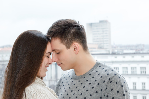 Loving couple touching noses outdoors with city view - Foto, afbeelding