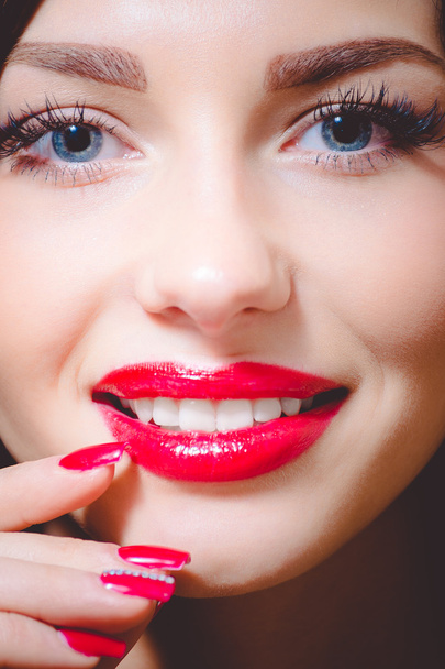 Attractive girl, tempting beuatiful young woman with blue eyes, long lashes, red lipstick and manicured nails - Fotó, kép