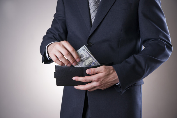 Businessman with money in studio on a gray background - Φωτογραφία, εικόνα