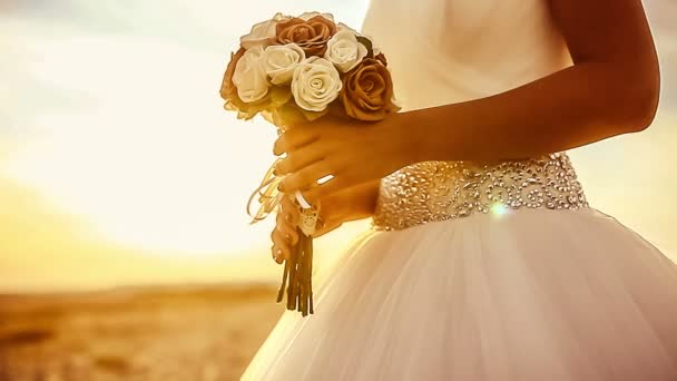 esküvő menyasszony tart esküvői csokor közelről nagy napnyugtakor a tengerparton, a külső lemegy a nap - Felvétel, videó