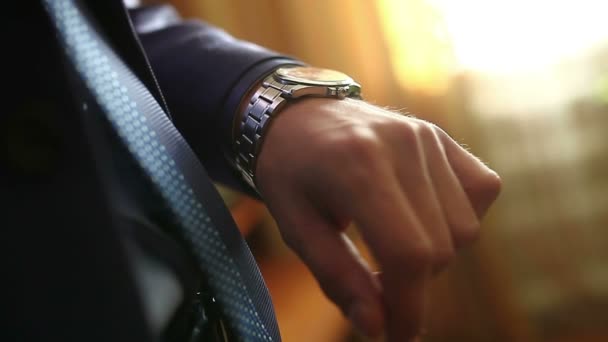 男男性ビジネスマンがスーツ立って彼の時計のビデオを見て、ウィンドウの時計します。 - 映像、動画