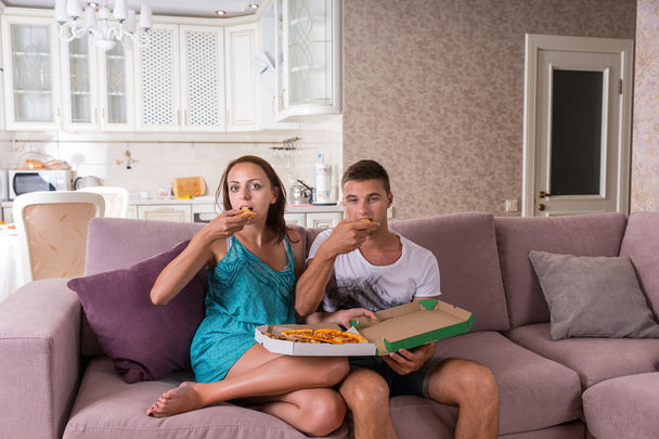 Jeune couple regardant la télévision et mangeant de la pizza
 - Photo, image