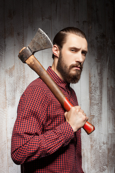 Cheerful young bearded man is carrying axe - Foto, Imagen
