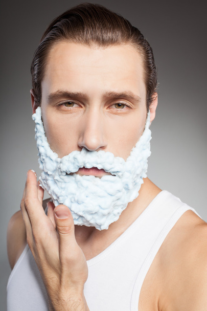 Attractive young bearded man shaves with joy - Fotó, kép