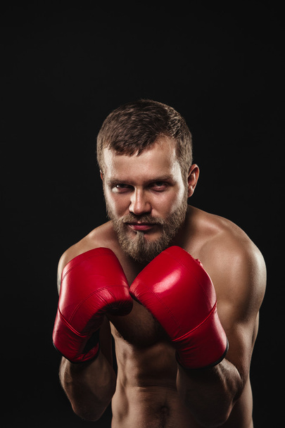 Athletic bearded boxer with gloves on a dark background - Φωτογραφία, εικόνα