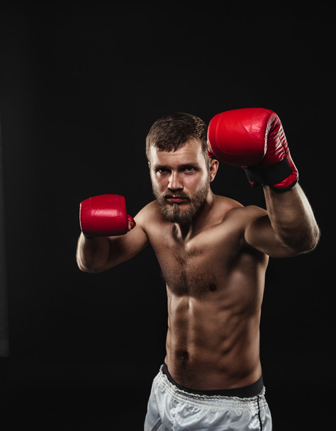 Athletic bearded boxer with gloves on a dark background - Foto, imagen