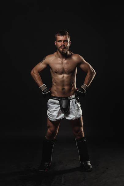 Athletic bearded boxer with gloves on a dark background - Fotoğraf, Görsel
