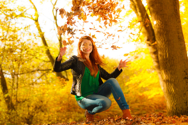 Girl relaxing in autumn park throwing leaves up in the air. - Zdjęcie, obraz