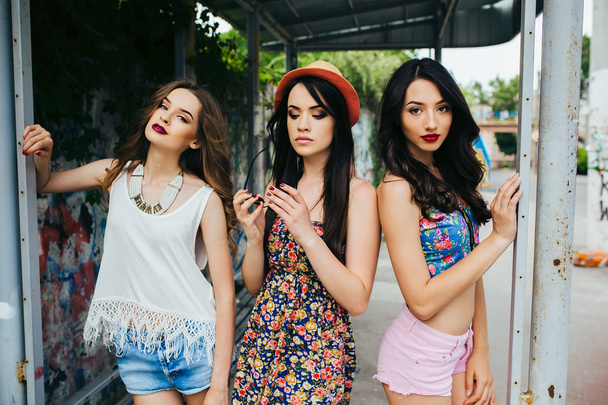 Tres hermosas chicas jóvenes en la parada de autobús
 - Foto, imagen