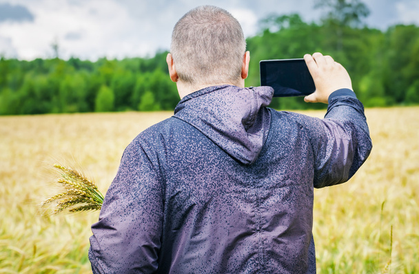 Farmer filmed with tablet PC on yellow cereal field - Zdjęcie, obraz