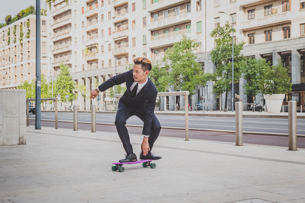 Young handsome Asian model posing with his skateboard - Foto, afbeelding