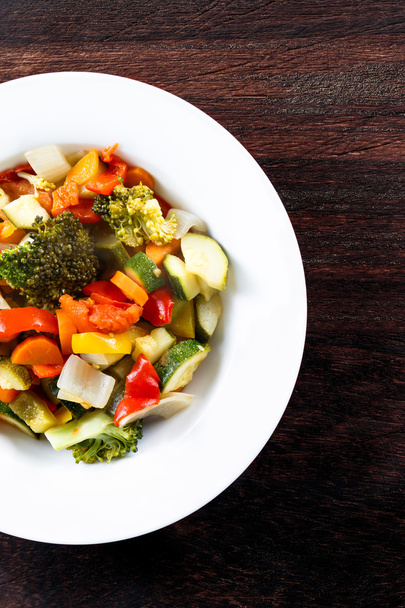 Gekookte geroosterde groenten gestoofd tomaten, wortelen, paprika's, Courgettes, broccoli, UI op platen. - Foto, afbeelding